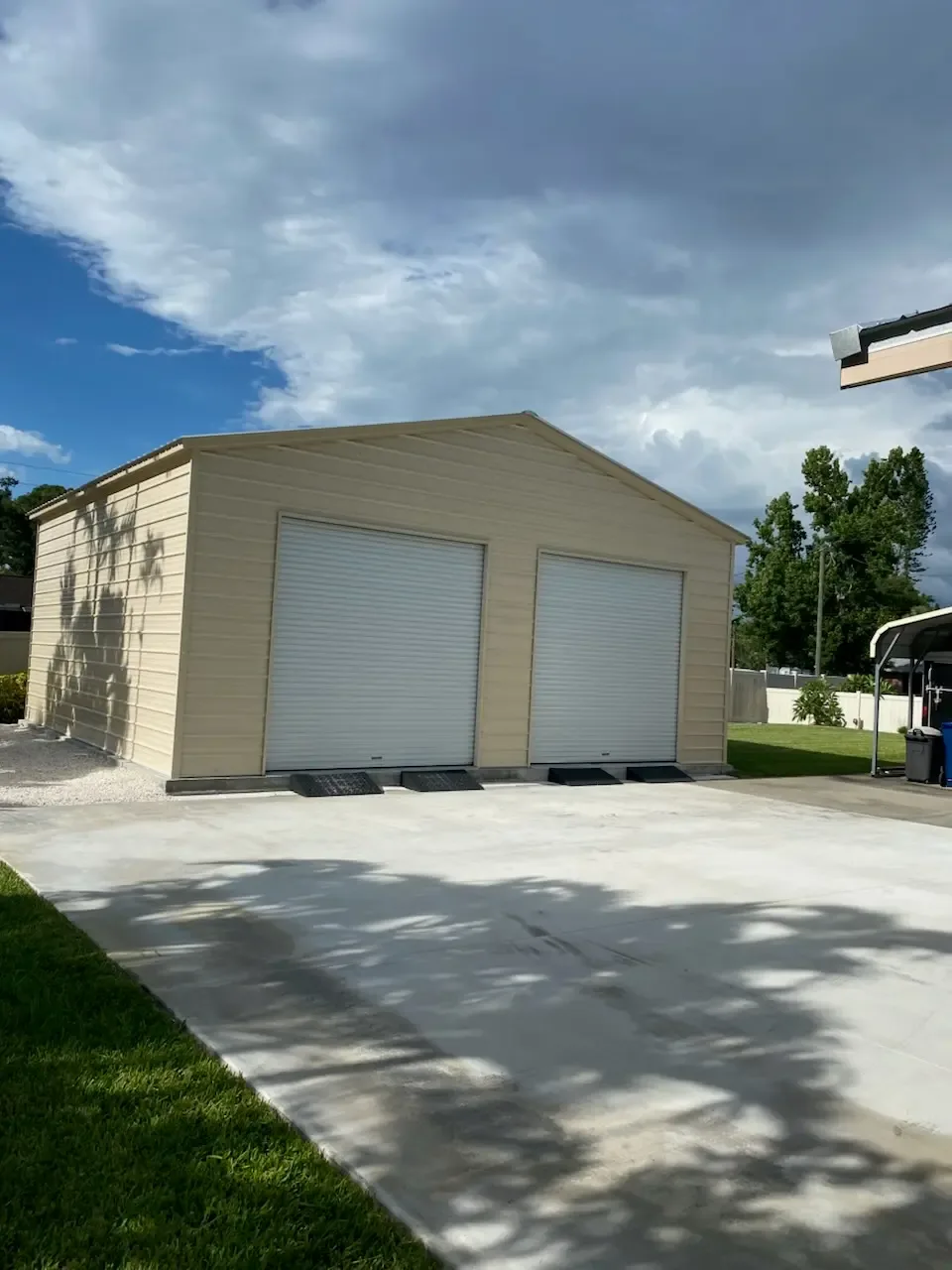 Two metal garages of the same footprint with different door, window and leg height configurations