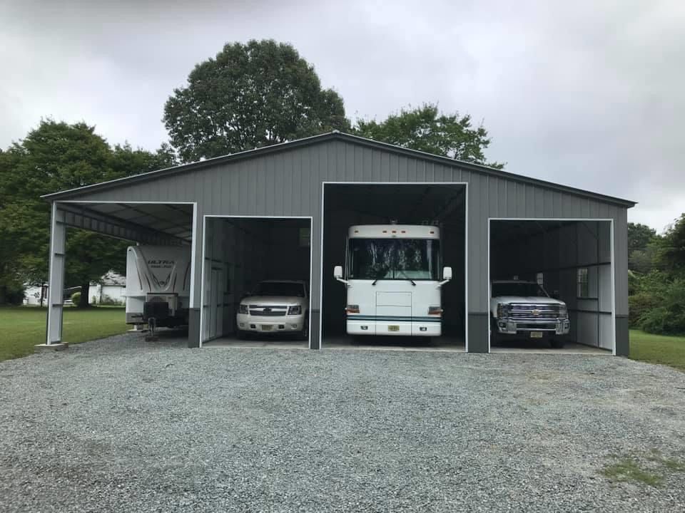 grey custom barn with rv and vehicles parked