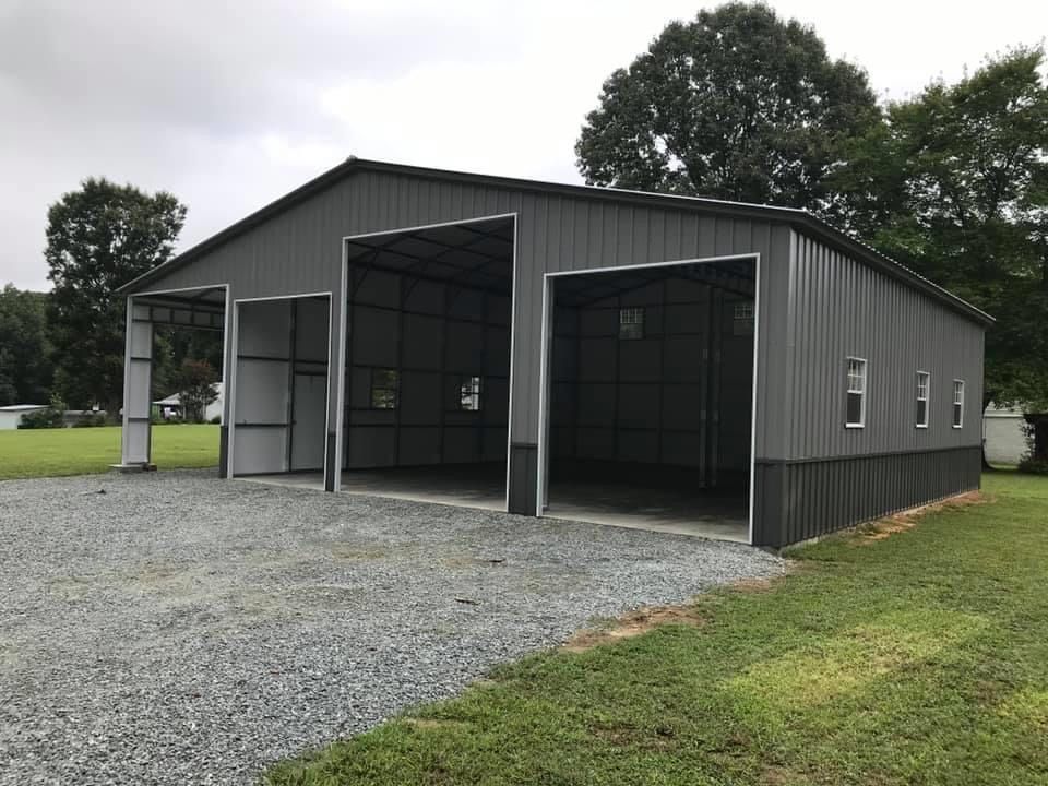 Two-tone gray custom barn with multiple rolling door entrances.